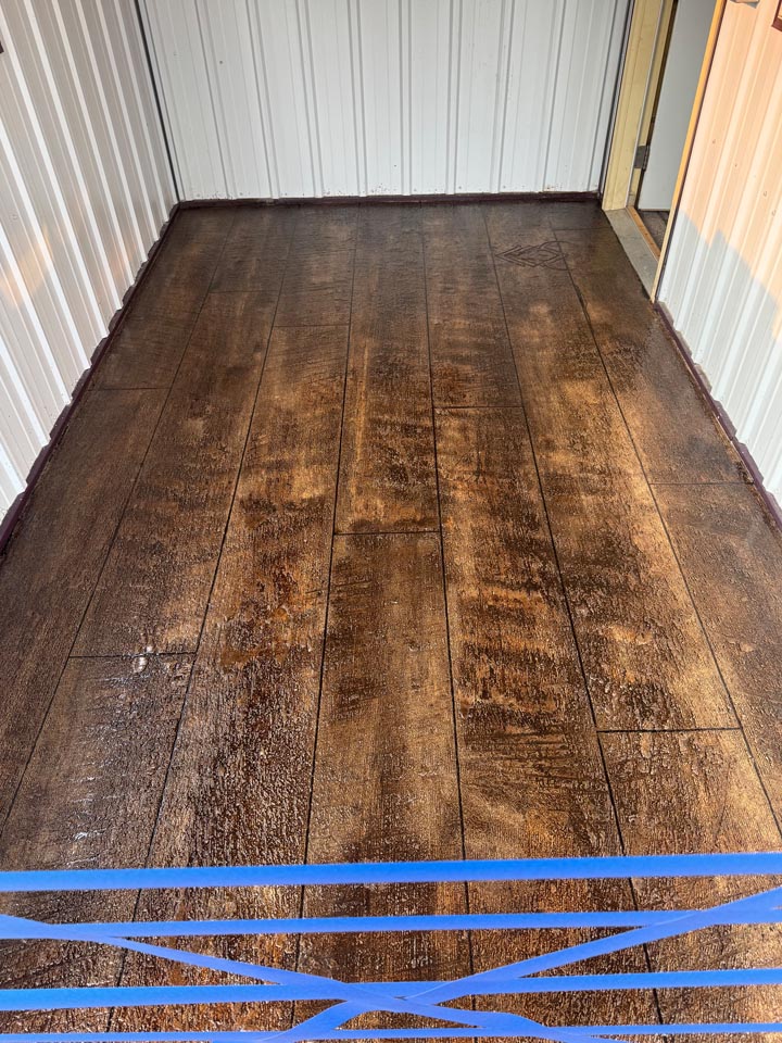 Metal building floor after - finished dark wood-plank stained concrete overlay