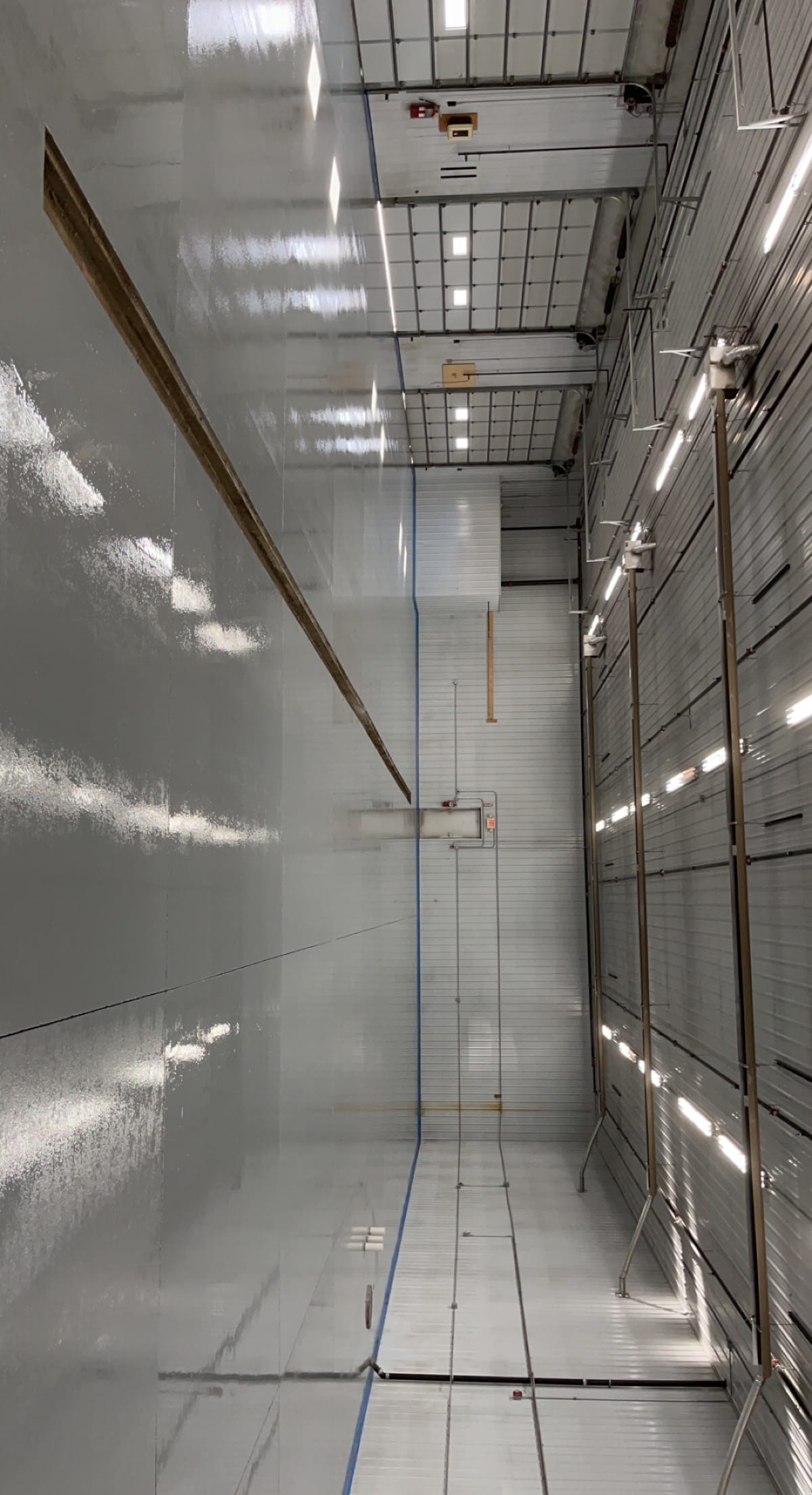 Commercial shop bay after, glossy solid grey epoxy floor with overhead doors and trench drain