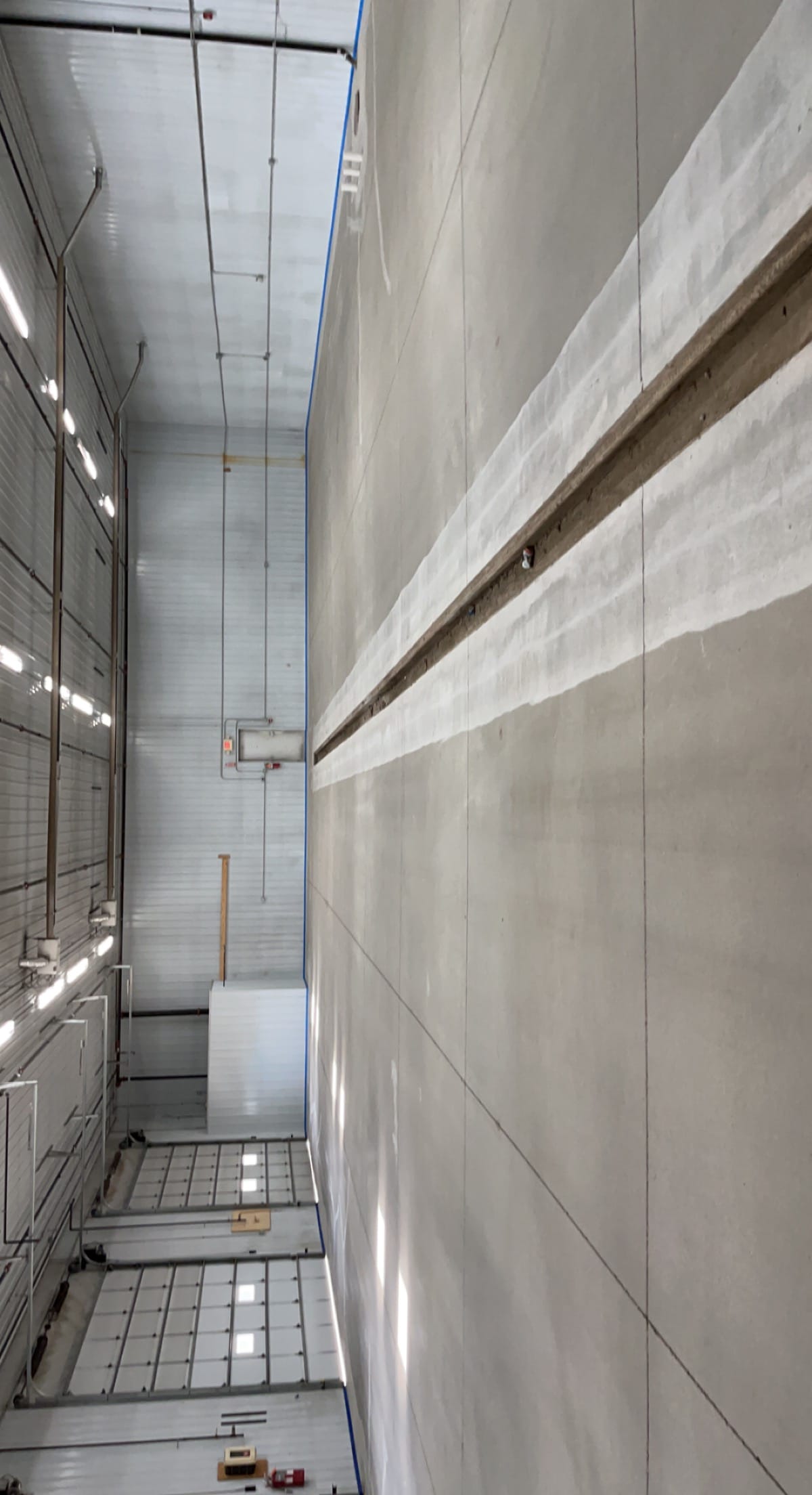 Commercial shop bay before, bare prepped concrete with overhead doors and center trench drain