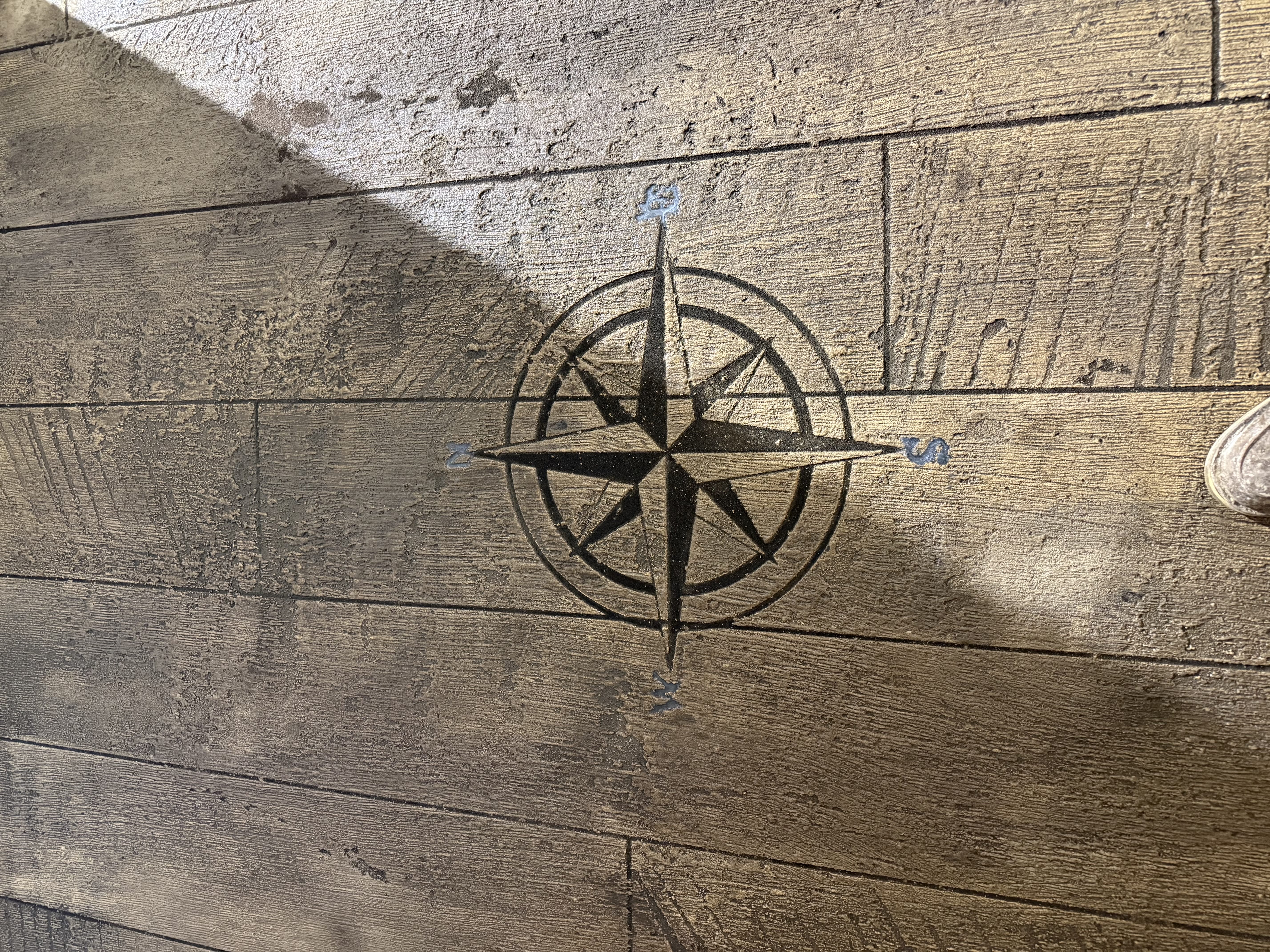 Close-up of compass-rose medallion stamped into wood-look concrete