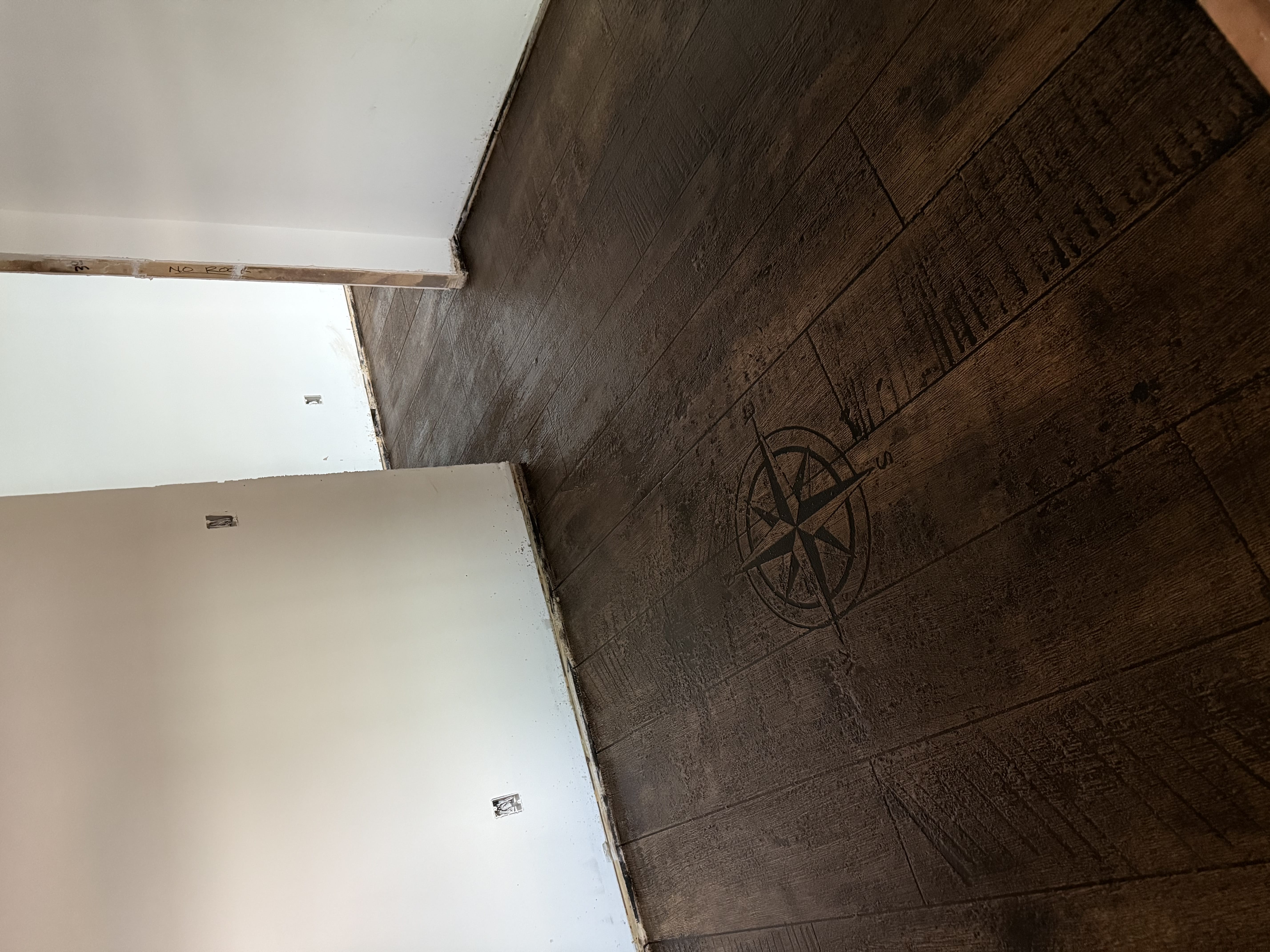 Wood-look stamped concrete floor with an inset compass-rose medallion